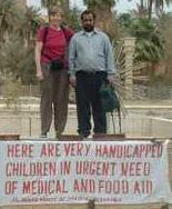 Dr. Claire Geraets met een Iraakse man en een spandoek: 'Hier zijn erg gehandicapte kinderen die dringend nood hebben aan medische en voedselhulp.'