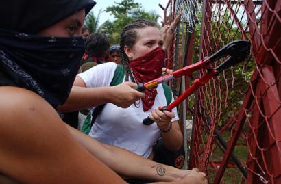 Anti-WTO protesters cut a fence protecting the World Trade Organization meeting