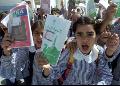 Palestinian school girls wave school books and shout slogans during a protest.
